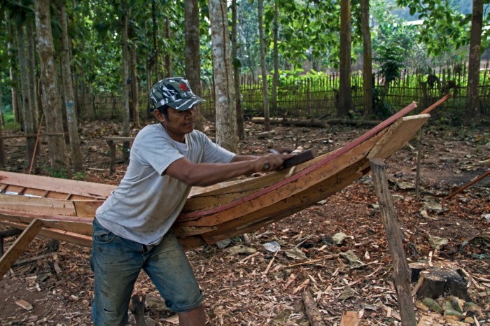 Man building a canoe near the village